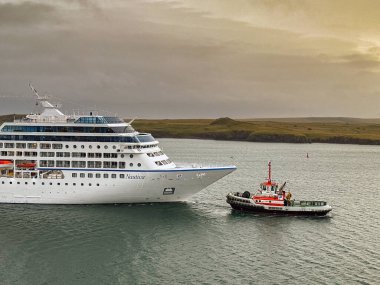 Reykjavik, İzlanda - 22 Ağustos 2024: Nautica yolcu gemisine sabahın erken saatlerinde bir römorkör yardım ediyor. Gemi Oceania Cruises tarafından işletiliyor..