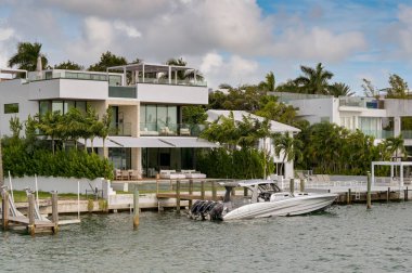 Miami, Florida, ABD - 1 Aralık 2023: Miami körfezindeki bir adanın dışında bir sürat teknesinin demirlediği lüks bir evin manzarası