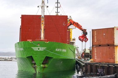 Qaqortoq, Greenland - 28 August 2024: Cargo ship North Viking unloading its cargo in the small port of the remote town of Qaqortoq. The vessel is operated by ESAN Shipping. clipart