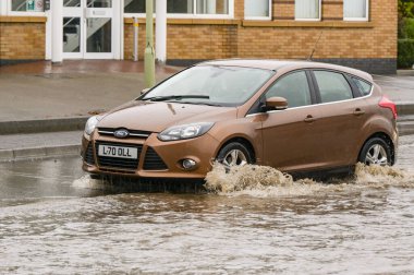 Treforest Industrial Estate, Wales, İngiltere - 24 Kasım 2024: Fırtına Bert 'ten sağanak yağış aldıktan sonra Treforest sanayi bölgesinde sel basmış bir yolda su taşıyan araba.