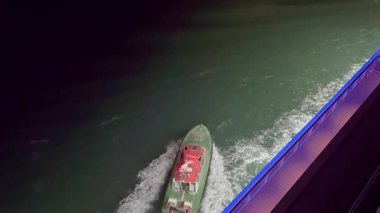 Lizbon, Portekiz - 13 Ocak 2025: Liman pilotu teknesi gece büyük bir yolcu gemisinin yanından ayrılıyor