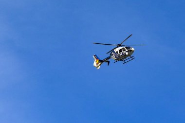 Vigo, İspanya - 14 Ocak 2025: Eurocopter EC 135P2 Polis helikopteri (kayıtlı EC-MDY) uçuşta açık mavi gökyüzüne karşı izole edildi