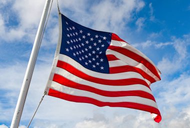 Amerika Birleşik Devletleri ulusal bayrağı Yıldızlar ve Şeritler, beyaz bulutlu mavi gökyüzüne karşı izole edilmiştir.