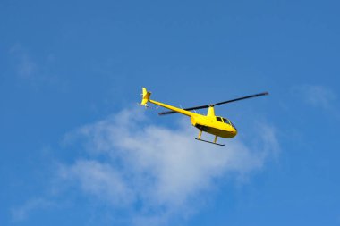 Sarı helikopter mavi gökyüzüne doğru uçuyor