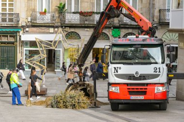 Vigo, İspanya - 14 Ocak 2025: Uzaktan kumandalı hidrolik vinç ve kova ile şehir merkezindeki yayaların oluşturduğu sokaktan toprak ve moloz toplayan bir kamyon şoförü