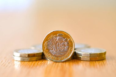 Tek bir İngiliz sikkesi. Kenarında duran bir İngiliz sikkesi. Diğer sikkelerle birlikte düz duruyor.