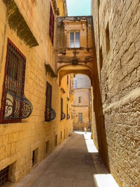 Mdina, Malta - 4 Ağustos 2023: Eski Mdina kentinin iki binayı birbirine bağlayan dar sokaklarından biri