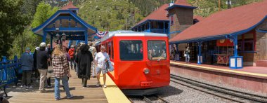 Manitou Springs, Colorado, ABD - 21 Mayıs 2025: Manitou ve Pike 's Peak tren yolu üzerinde dağın eteğindeki merkez istasyonda trene binen insanların panoramik görüntüsü.