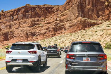 Moab, Utah, ABD - 25 Mayıs 2025: Moab 'daki Arches Ulusal Parkı' na girmek için kayalıkların altında kuyruğa giren arabalar