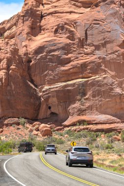 Moab, Utah, ABD - 25 Mayıs 2025: Moab 'daki Arches Ulusal Parkı' nda kayalıkların altında giden arabalar