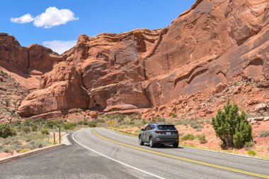 Moab, Utah - 25 Mayıs 2025: Moab, Utah 'taki Arches Ulusal Parkı' nda uzun kayalıkların altında dolambaçlı bir yolda araba sürüyor. Kimse yok..