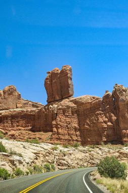 Moab, Utah 'taki Arches Ulusal Parkı' nda yüksek kayalıkların altında viraj yolu. Kimse yok..