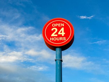 Mavi gökyüzüne karşı 24 saat açık işaret. İnsan yok, boşluğu kopyala.