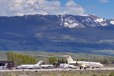 Jackson Hole, Wyoming, ABD - 27 Mayıs 2025: Gulfstream G450 özel yönetici jeti (N251HR plakalı) ve Jackson Hole havaalanındaki diğer şirket jetlerinin manzaralı görüntüsü.