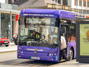 Cardiff, Wales, İngiltere - 16 Temmuz 2025: Cardiff şehir merkezinde elektrikli kamu hizmeti otobüsüne binen yolcular. Hizmet kardiyodür otobüsü tarafından işletilir..