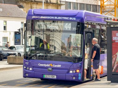 Cardiff, Wales, İngiltere - 16 Temmuz 2025: Cardiff şehir merkezinde elektrikli kamu hizmeti otobüsüne binen yolcular. Hizmet kardiyodür otobüsü tarafından işletilir..