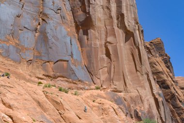 Moab, Utah, ABD - 25 Mayıs 2025: Kaya tırmanışçısı dağların ölçeğini yükselterek bir kaya yüzeyi üzerinde duruyor