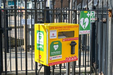 Paignton, Devon, İngiltere, İngiltere - 24 Nisan 2025: Paignton Tren İstasyonu dışındaki demiryollarına bağlı tıbbi acil durumlarda kullanmak üzere bir kalp çalıştırıcı defibrilatörü içeren kutu.