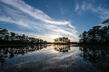 Sunset cloudscape over and reflected in water at Long Pine Key in Everglades National Park, Florida.
