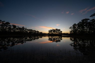 Sunset cloudscape over and reflected in water at Long Pine Key in Everglades National Park, Florida.