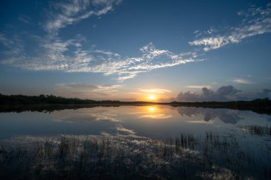 Colorful sunrise cloudscape reflected in calm water of Nine Mile Pond in Everglades National Park, Florida.