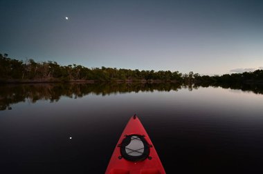Everglades Ulusal Parkı, Florida 'daki Coot Bay' de kırmızı kano. Akşam alacakaranlığı sırasında arka planda ay var..