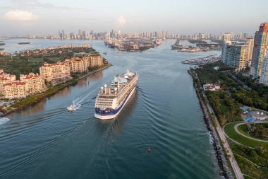 Miami Beach, Florida - 22 Temmuz 2023 - Miami Limanı 'na gün doğumunda Miami Limanı' na giriş yapan yolcu gemisi, arka planda Fisher Adası, South Pointe Park ve Miami silueti ile birlikte.