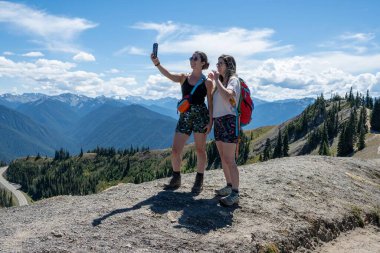 Güneşli yaz öğleden sonra Olympic Ulusal Parkı 'ndaki Kasırga Tepesi yolunda selfie çeken iki kız kardeş..