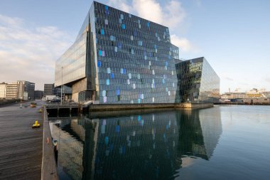 Reykjavik, İzlanda - 4 Eylül 2023 - Harpa Konser Salonu güneşli bir sonbahar sabahı Reykjavik Limanı 'nın sakin sularına yansıdı.
