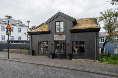 Reykjavik, İzlanda - 3 Eylül 2023 - Sonbahar bulutları altında karakteristik kıvrımlı demir bina yapısını gösteren renkli sokak sahnesi.