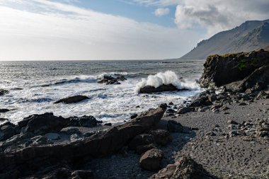 İzlanda 'nın engebeli doğu kıyısında fırtınalı denizler güneşli bir sonbahar sabahında güçlü rüzgarlarla.