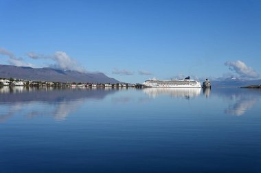 Akureyri, İzlanda - 9 Eylül 2023 - Akureyri ve çevresindeki manzara berrak güneşli bir sonbahar sabahı sakin sulara yansıdı.