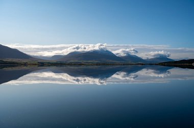 Akureyri, İzlanda - 9 Eylül 2023 - Akureyri ve çevresindeki manzara berrak güneşli bir sonbahar sabahı sakin sulara yansıdı.