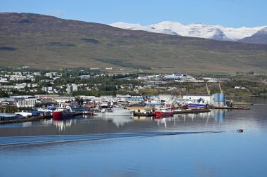 Akureyri, İzlanda - 9 Eylül 2023 - Akureyri ve çevresindeki manzara berrak güneşli bir sonbahar sabahı sakin sulara yansıdı.