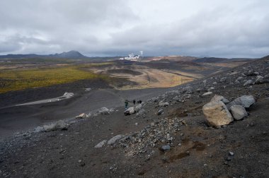 Myvatn, İzlanda 'nın doğusundaki Hverfjall kraterinin kenarına giden yürüyüşçüler sonbahar öğleden sonraları arka planda jeotermal alan ile bulutlu hava manzarası oluşturuyorlar...