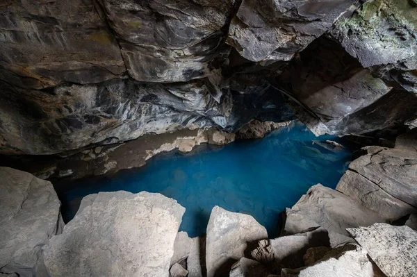 Grjotagja lav mağarasında mavi havuz ve Myvatn, İzlanda 'da sonbahar öğleden sonra bulutları altında çatlak.