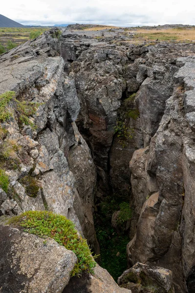 Grjotagja lav mağarası ve Myvatn, İzlanda 'da sonbahar öğleden sonra bulutları altında çatlak.