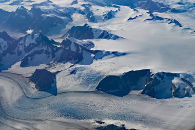 Güneşli bir sonbahar gününde Grönland 'ın güneyindeki dağların, kar tarlalarının ve buzulların havadan görünüşü.