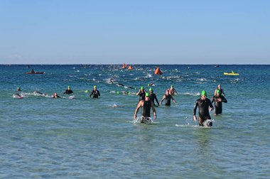 Panama City Beach, Florida - 4 Kasım 2023 - Ironman yarışmacıları güneşli bir sonbahar sabahı 2023 'ün yüzme bölümünden sonra okyanustan ayrıldılar.