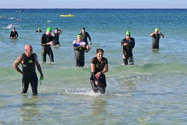 Panama City Beach, Florida - 4 Kasım 2023 - Ironman yarışmacıları güneşli bir sonbahar sabahı 2023 'ün yüzme bölümünden sonra okyanustan ayrıldılar.