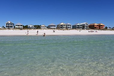 Panama City Plajı, Florida - 4 Kasım 2023 - Güneşli bir sonbahar gününde arka planda evleri olan plajın keyfini çıkaran insanlar.