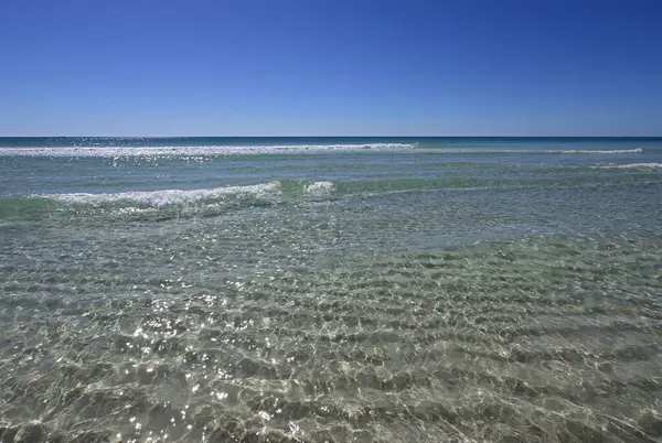 Bulutsuz güneşli bir günde Panama City Beach, Florida 'nın beyaz kum ve kristal berrak suları.