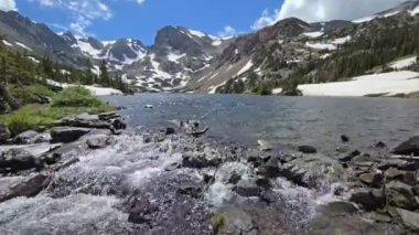 Colorado, Indian Peaks Wilderness 'da, Isabelle Gölü' nden akan erimiş su dramatik yaz bulutları altında 4K.