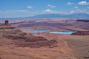 Moab, Utah yakınlarındaki Dead Horse Point Eyalet Parkı 'ndan gelen potasyum buharlaşma göletlerinin manzarası güneşli yaz bulutları altında..