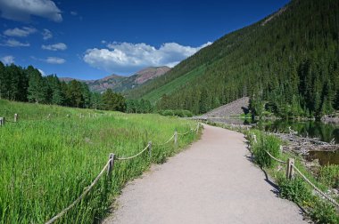 Güneşli bir öğleden sonra, dramatik bir yaz bulutu altında Maroon Gölü 'nün etrafında Maroon Bells manzaralı yürüyüş..