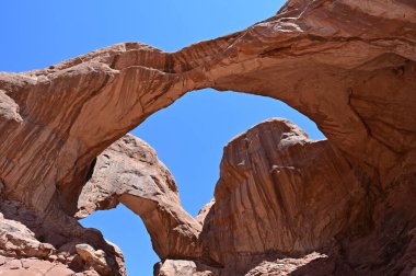 Moab, Utah yakınlarındaki Arches Ulusal Parkı 'nda açık mavi gökyüzünün altında çift kemer düzeni..