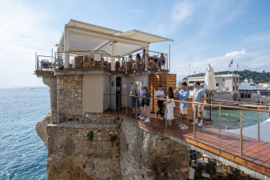 Nice, Fransa - 20 Eylül 2024: İnsanlar Akdeniz üzerinde kaya sütunu üzerine inşa edilmiş popüler restoran Le Plongeoir 'de masaları bekliyor,