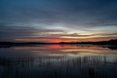 Colorful sunrise cloudscape reflected in calm water of Nine Mile Pond in Everglades National Park, Florida.