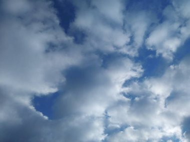 Bir köyün üzerinde çok renkli bulutlar uçuşuyor.