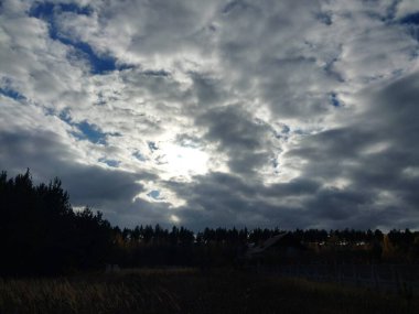 Bir köyün üzerinde çok renkli bulutlar uçuşuyor.